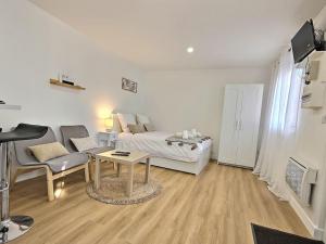 ein weißes Wohnzimmer mit einem Bett und einem Tisch in der Unterkunft Cosy Des Rêves in Villiers-sur-Marne