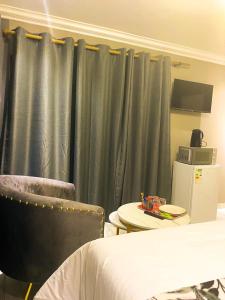 a bedroom with green curtains and a table and a bed at Kwena Guesthouse in Groblersdal +19 photos