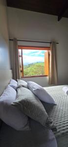 a bedroom with a bed with pillows and a window at Pousada Charme da Mantiqueira in Passa Quatro