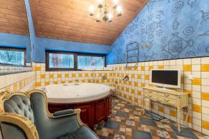 un bagno con vasca e tv a parete di Vilos NEMUNO SLĖNIS Liuxas a Birštonas