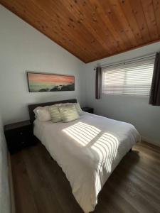 a bedroom with a white bed with a wooden ceiling at Newport Beach Rendezvous in Newport Beach