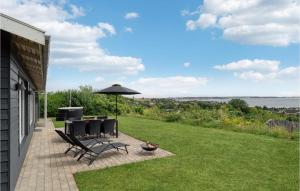 eine Terrasse mit Tisch und Stühlen und einem Sonnenschirm in der Unterkunft 3 Bedroom Beautiful Home In Ebeltoft in Ebeltoft + 13 Fotos