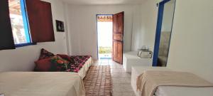 a room with two beds and a door to a room with a window at Hostel do Bem-Viver in Itaúnas