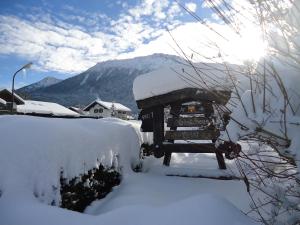 a car covered in snow with the sun behind it at Gästehaus Geist in Ruhpolding