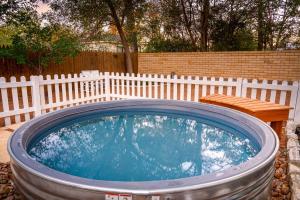 a hot tub in a yard with a wooden fence at LeMay Haus - Fire Pit, Heated Pool & Close to Main in Fredericksburg