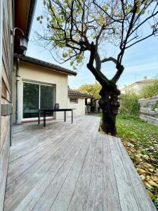 una terrazza in legno con un albero sul lato di una casa di LAbri-Côtier - Maison chaleureuse - Jardin a Tolosa