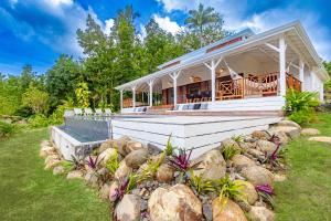 a white house with a porch and some rocks at Villa Ti Piou in Deshaies