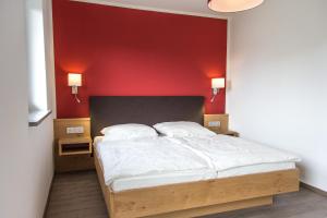 ein Schlafzimmer mit einem Bett mit einer roten Wand in der Unterkunft Ferienwohnungen Hopfensee in Füssen