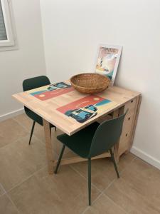 a wooden table with two chairs and a basket on top at Appartement rez-de-chaussée in Lit-et-Mixe +6 photos