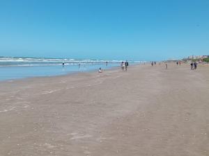 a group of people walking on the beach at Mar de Ana, Frente al mar, interno a una cuadra del centro in San Bernardo