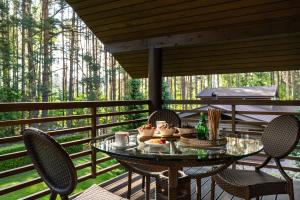 a table and chairs on a porch with a table and drinks at Woodland Retreat Lodge in Vallapalu