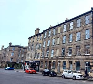 a large brick building with cars parked in front of it at Spacious Victorian Apartment in Edinburgh City in Edinburgh