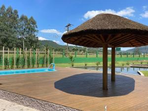 a large straw umbrella sitting next to a swimming pool at Casa Sítio Caminhos Da Serra in Feliz
