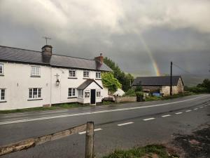 a rainbow in the sky over a house and a road at Dinas Castle Inn (The Dragons Back) in Talgarth