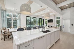 une cuisine avec des armoires blanches et une table avec des chaises dans l'établissement Bearfoot By The Sea, à Santa Rosa Beach