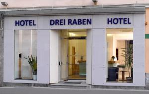 a man is looking out a window in front of a building at Hotel Drei Raben in Graz