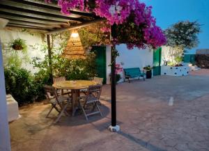 a table and chairs under a pergola with purple flowers at BUGANVILLA MOLINO in Tinajo
