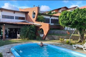 a woman in a pool in front of a house at mansão com churrasqueira sinuca piscina aquecida in Natal