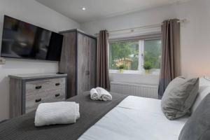 a bedroom with a bed with a television on the wall at Prime Location, Modern 2br House in Sheffield