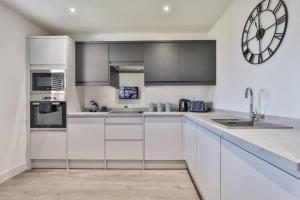 a kitchen with white cabinets and a clock on the wall at Modern, Cosy Whole House Wifi Close To Attractions in Sheffield +34 photos