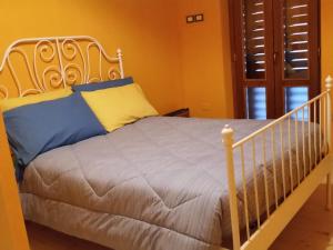 Una cama blanca con almohadas azules y amarillas. en Lo Scoiattolo Country House, en Montorio al Vomano