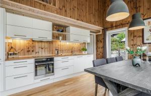 a kitchen with white cabinets and a wooden wall at Nice Home In Gol With Wifi in Golsfjellet