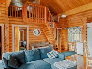 a living room with a blue couch and a wooden staircase at Matikkala Cottages in Ruokolahti