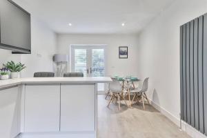 a white kitchen with a table and chairs at 3 Bed Refurbished, Modern House, Wifi, Patio Area in Sheffield