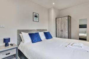 a bedroom with a large white bed with blue pillows at 3 Bed Refurbished, Modern House, Wifi, Patio Area in Sheffield