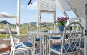 a white table and chairs on a porch with windows at Holiday Home Ringkøbing With Fireplace Ii in Ringkøbing