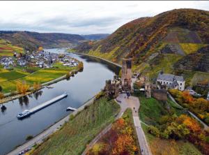 a castle on a hill next to a river at Ferienhaus Mosel-Wohnen l in Bruttig-Fankel