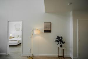 a white room with a bed and a lamp at Chic Urban Retreat in Heart of LA, 2 Bedroom and 1 Loft in Los Angeles
