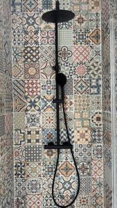 a bathroom with a tile wall with a black object on it at Casa Cubana in Roubaix