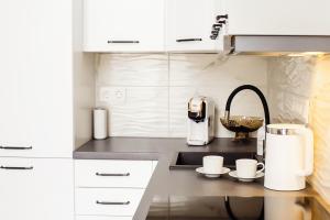 a kitchen with white cabinets and a coffee maker on a counter at Edvin Loft x Free parking in Vilnius