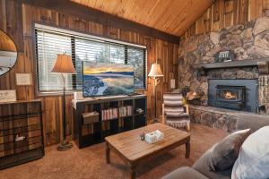 a living room with a fireplace and a stone wall at Cozy Cabin - Quiet Area, Fireplace, Smart TV, Fenced Yard in Big Bear City