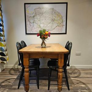 a table with a vase of flowers and a map at The Old Flint Bank Cottage in Harleston +4 photos