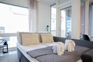a bed with white towels on it in a room with windows at Hostit Arctic Apartments By BookLapland in Rovaniemi