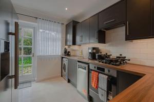 Una cocina con gabinetes negros y un horno de estufa. en Stylish Putney Family Home-Close to Central London, en Londres