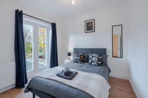 Un dormitorio con una cama y una ventana grande. en Stylish Putney Family Home-Close to Central London, en Londres