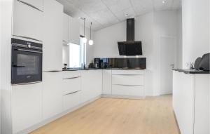 a kitchen with white cabinets and a wooden floor at Four-Bedroom Holiday Home In Ringkobing in Ringkøbing