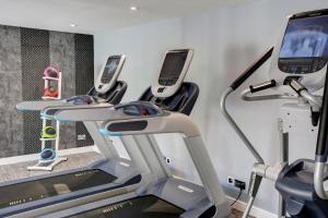 eine Reihe von Laufbändern in einem Fitnessstudio mit Handys in der Unterkunft Frensham Pond Country House Hotel & Spa in Farnham