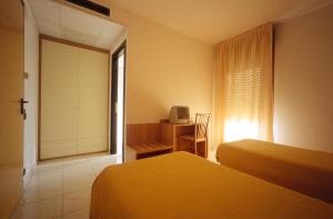 a bedroom with two beds and a desk and a window at Motel Monterosa in Vogogna