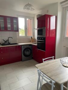 a kitchen with red cabinets and a washing machine at Le gîte de Myrlène-30min Parc Fédéral-12min CNPE CAUTION OBLIGATOIRE SWIKLY in Sully-sur-Loire