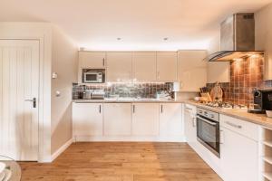 a kitchen with white cabinets and a stove top oven at St Leonard's Luxury Lodge, St Andrews in St. Andrews