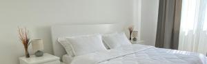 un letto bianco con lenzuola e cuscini bianchi in una camera da letto di FGB Lodi a Lodi
