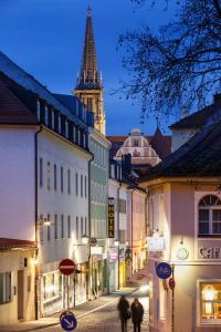 un grupo de personas caminando por una calle de la ciudad por la noche en Hotel am Peterstor en Regensburg