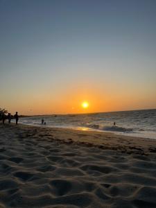 パルナイバにあるCasa litoralの水中の人々と一緒に海岸に沈む夕日