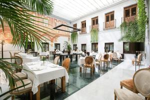 a restaurant with tables and chairs and plants at Hospes Palacio del Bailio, a Member of Design Hotels in Córdoba
