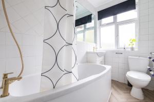 a white bathroom with a tub and a toilet at Astrid Room - Kingsize minimalist room in Luton in Luton