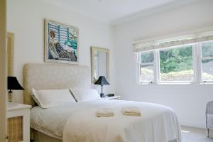 a white bedroom with a bed with two towels on it at Macksville Cottage Robertson in Robertson